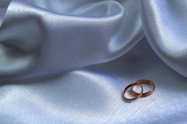 Altın alyanslar saten kumaşın üzerinde.