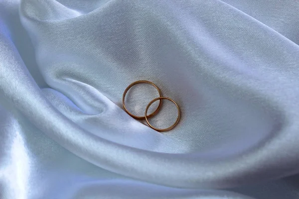 Altın alyanslar saten kumaşın üzerinde.