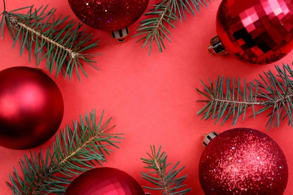 赤いちらつきクリスマスのおもちゃはトウヒの小枝と赤い背景にあります — ストック写真