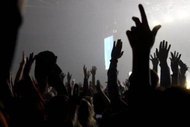 Konser salonundaki bulanık fotoğrafçılar ellerini sallıyor.