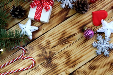 Hediye kutusu ahşap arka planda Noel eşyalarıyla çevrili.