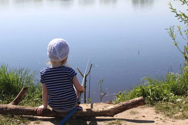 Niña Sienta Cerca Del Agua Atrapa Pez Con Una Caña — Foto de Stock