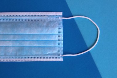 Tıbbi maske mavi bir arka planda yatıyor.