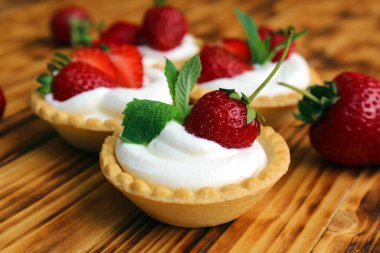 Tahta bir masada kremalı ve çilekli turta.