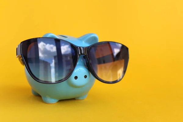 Piggy piggy bank with sunglasses on a yellow background