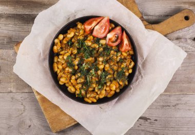 Ahşap arka plan üzerinde siyah bir tabakta pişmiş fasulye