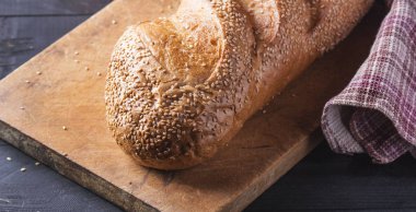 Taze somun ahşap bir masaya susam serpilir. Delici