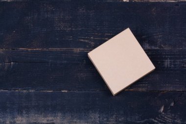 Koyu ahşap arka planda küçük bir karton kutu.