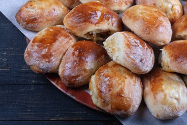 Koyu ahşap arka planda lahanalı bir sürü ev yapımı turta.