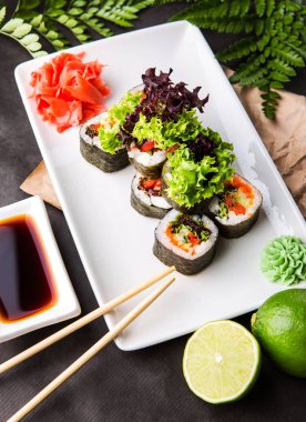 Vejetaryen sebze ile nori soya sosu ve yemek çubukları ile siyah bir zemin üzerine rulo