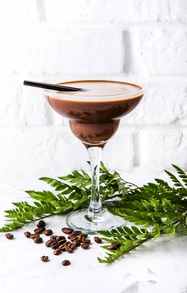 cold summer coffee drink with coffee beans and greens on a white concrete background