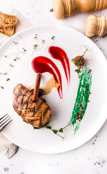 Fırında ördek fileto berry sos ve beyaz bir arka plan üzerinde hizmet veren güzel bir restoranda kabuk tarçın