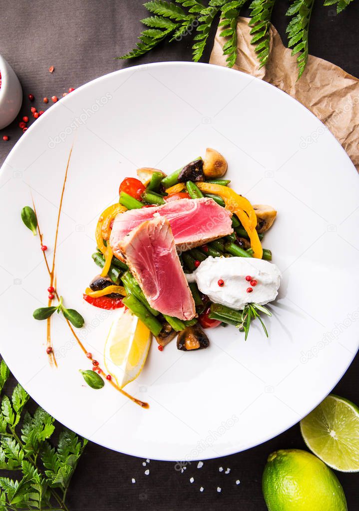 tuna with vegetables, beans, mushrooms, bell pepper on a black background with lime