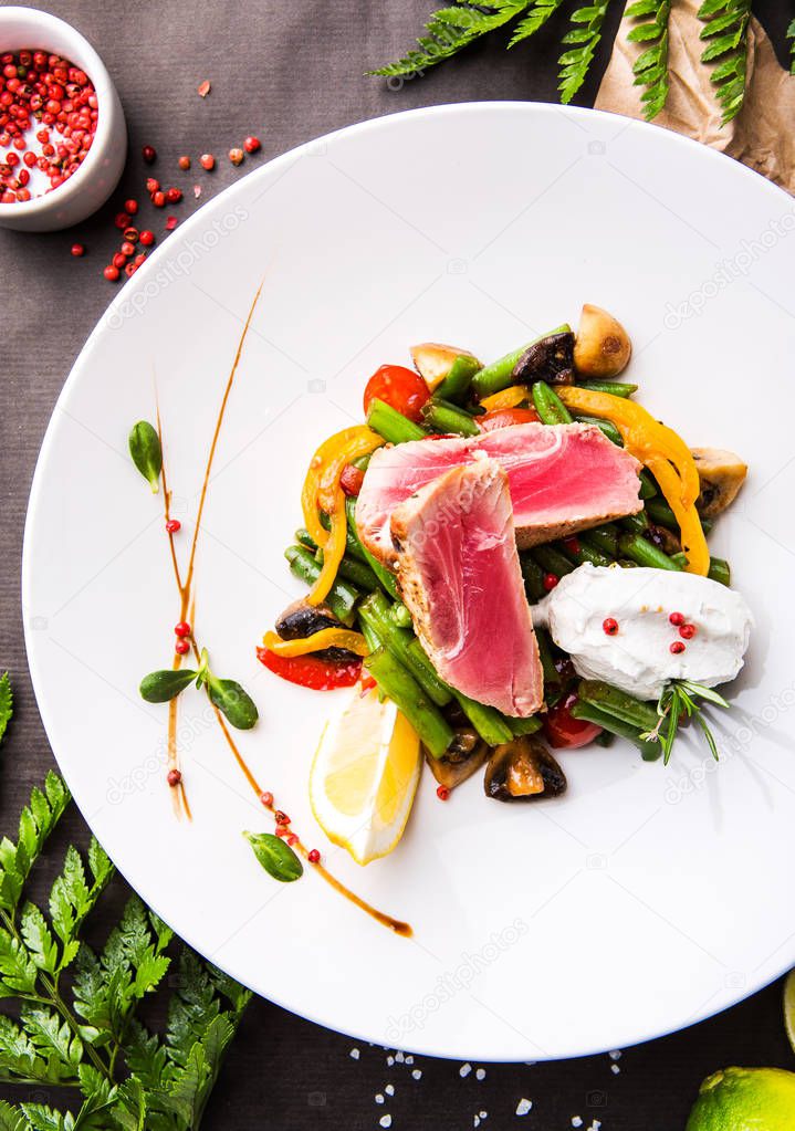 tuna with vegetables, beans, mushrooms, bell pepper on a black background with lime
