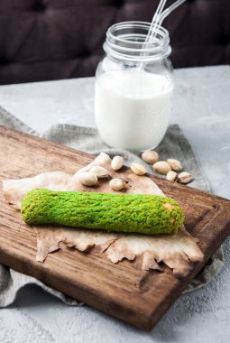 Bir şişe süt ile ahşap bir gemide lezzetli fıstık yeşil pasta