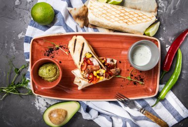 Meksikalı börek yemek tavuk, biber ve Mısır ile guacamole avokado ve kireç ile hizmet veren bir beton gri arka plan üzerinde