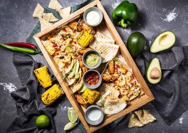 Meksika aperatifler, tacos, ekmeği, ızgara mısır, büyük bir set kanatları ve gri beton zemin üzerine güzel bir ortamda farklı sos ızgara