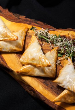 Yakın çekim karanlık bir arka plan ahşap bir gemide phyllo hamur işi üçgenler