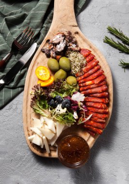 Salam, jambon, et Şarküteri chorizo bree peynir, zeytin, badem fındık, incir ile kesme tahtası üzerinde bir gri beton şık arka plan yakın çekim jam