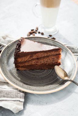 Gri bir plaka ile bir fincan çikolatalı kek dilim latte kahve