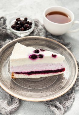 Böğürtlenli yoğurt mousse kek bir fincan çay ile gri bir plaka üzerinde