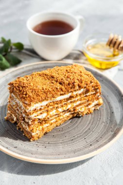 Bir fincan çay ile gri bir tabakta ekşi krema ile çok katmanlı tatlım pasta