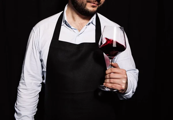 在黑暗的背景下 侍酒师手里拿着红酒在晃动葡萄酒杯 — 图库照片