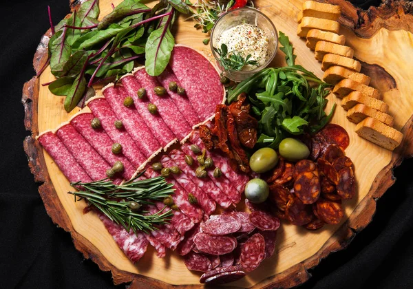 Delicatessen Embutidos Salami Rodajas Con Vegetación Aceitunas Una Tabla Cortar —  Fotos de Stock