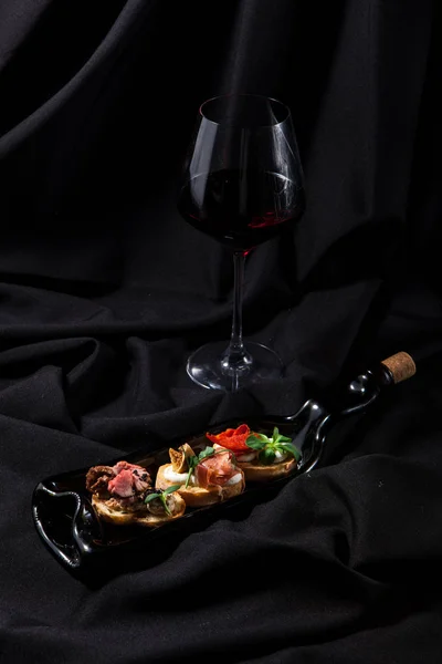 在黑暗时尚的背景上与葡萄酒的三系布鲁切塔 — 图库照片