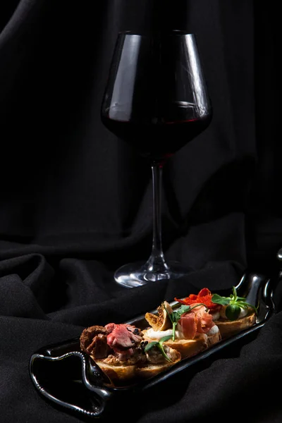 Trio of bruschetta with wine on dark stylish background