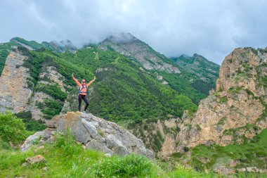 Bir sırt çantası içinde bir dağ Vadisi ile duran genç kadın.