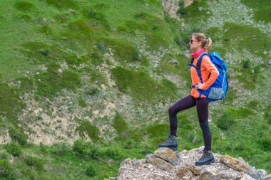 Bir sırt çantası içinde bir dağ Vadisi ile duran genç kadın.