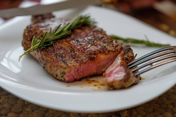 Beef steak with a sprig of rosemary on a plate. Image.