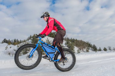 A young man riding fat bicycle in the winter. Fat tire bike. clipart