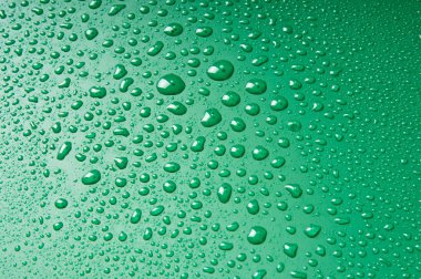 Su damlaları, yeşil bir arka plan üzerinde farklı boyutlarda