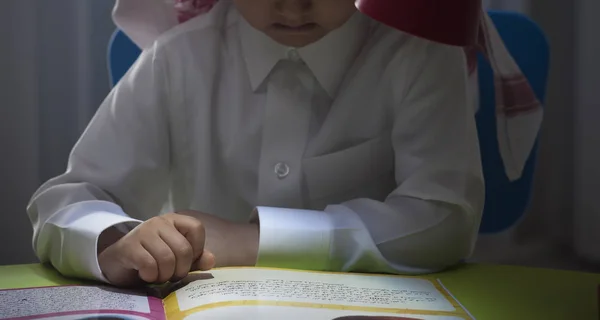 Suudi çocuk bir masada bir hikaye okuma lambası ile yakın çekim