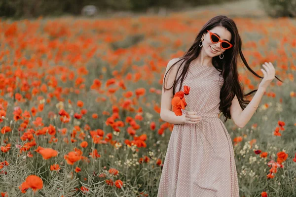 Mädchen posiert im Mohnfeld mit roter Brille Stockfoto