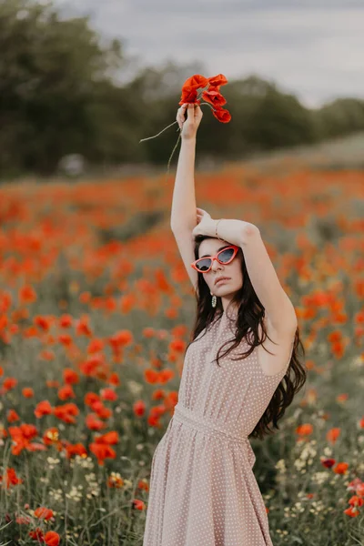 Mädchen posiert im Mohnfeld mit roter Brille Stockbild