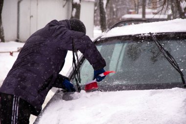 Bir adam kazıyıcı arabasından kar kış kar fırtınaları sırasında araç pencereleri krema