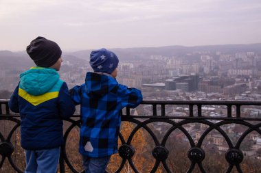 İki arkadaş bir büyük şehir kavramsal fotoğrafçılık izlerken yüksek bir dağın üzerinde duran