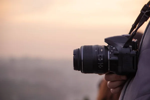 Arka plan günbatımı yüksek bir dağın üzerinde bir kamera ile fotoğrafçı