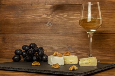 Camembert peyniri, fındık ve tatlı üzüm beyaz SEK şarap bir bardak arka plan üzerinde kıyılmış