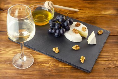Bir bardak beyaz arka plan üzerinde Camembert peyniri, ceviz, bal ve tatlı üzüm şarap Kuru