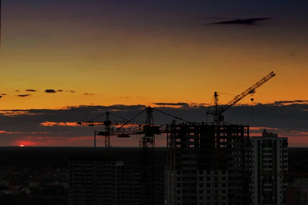 Şaşırtıcı günbatımı gökyüzü arka plan üzerinde endüstriyel İnşaat vinçleri — Stok fotoğraf