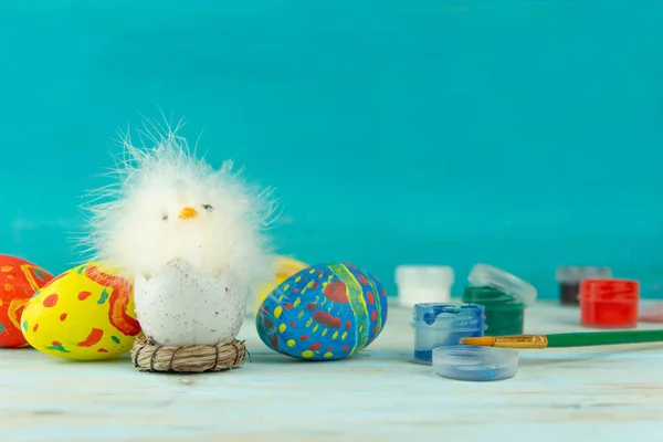 Páscoa bebê galinha ao lado de ovos no fundo de madeira azul — Fotografia de Stock