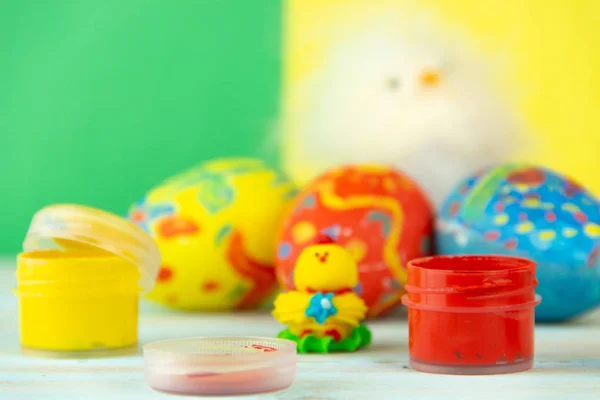 Πασχαλινά αυγά σε πολύχρωμη ξύλινη φόντο με κοτόπουλο μωρό, βαφές και βούρτσα — Φωτογραφία Αρχείου