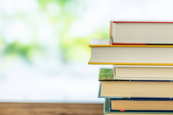 Pila de libros en la sala de la biblioteca en tabel y árboles borrosos en la calle volver al concepto de la escuela — Foto de Stock