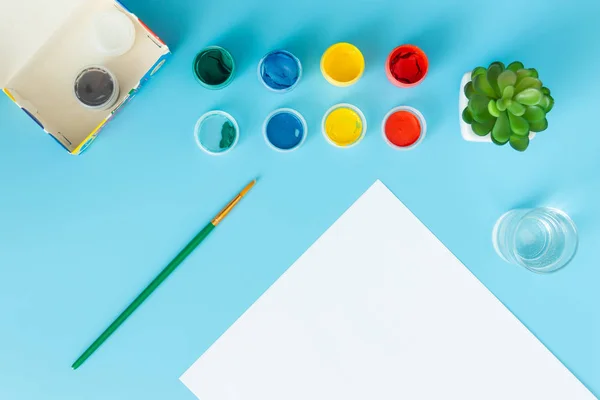 Set para pintar pinturas hoja blanca de papel con pinturas verdes suculentas, multicolores y pincel sobre fondo azul con lugar para la inscripción — Foto de Stock