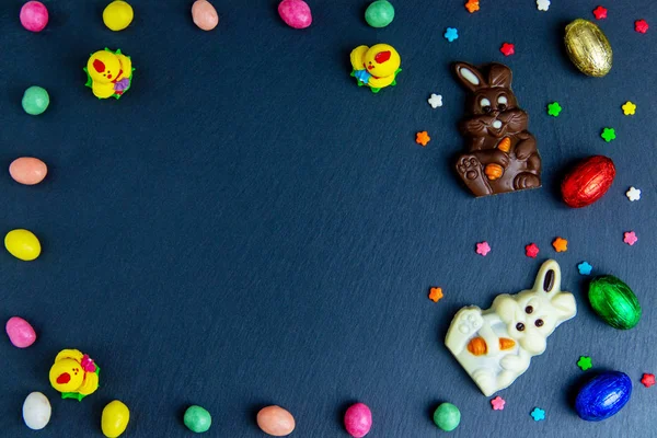 Πασχαλινό ευχετήρια κάρτα με πολύχρωμο πλαίσιο καραμέλα, αυγά σοκολάτας και καραμέλες. Κορυφαία προβολή σε πέτρινο τραπέζι με χώρο για τους χαιρετισμούς σας — Φωτογραφία Αρχείου