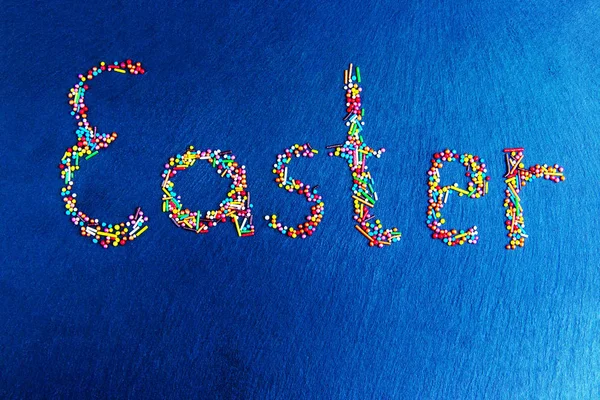 Húsvét fogalom sokszínű cukorka van fektetett ki-ban forma-ból Húsvét-ra egy sötét kék háttér — Stock Fotó
